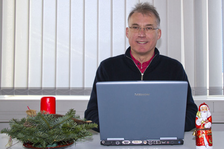 Ein Mann sitzt zufrieden vor seinem Laptop.