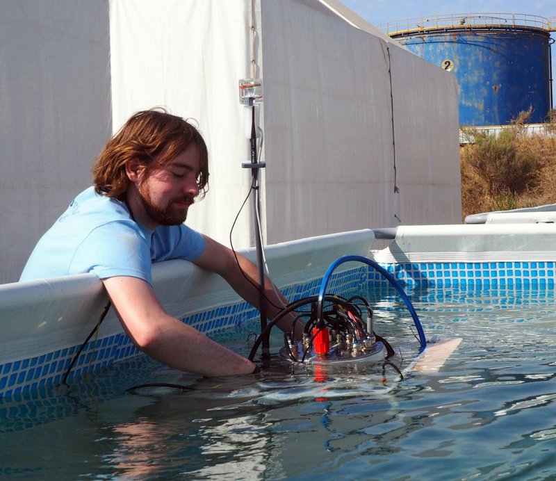 Ein Mann setzt eine Unterwassermaschine in einen Pool ein.
