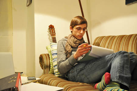 Ein Student sitzt lesend auf einem Sofa.