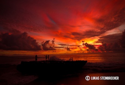 Über dem Meer bilden Wolken und Sonnenuntergang ein farbenfrohes Spektakel.