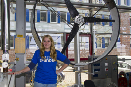 Eine Studentin steht in einer Halle, neben ihr ein großer Propeller.