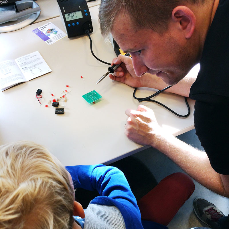 Hannes Eilers demonstriert einem Kind das Löten elektronischer Bauteile