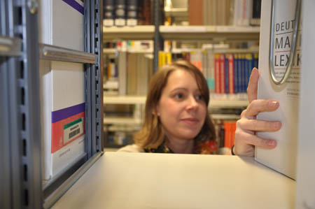 Eine Frau durchforstet die Regale der Bibliothek, der FH Kiel.