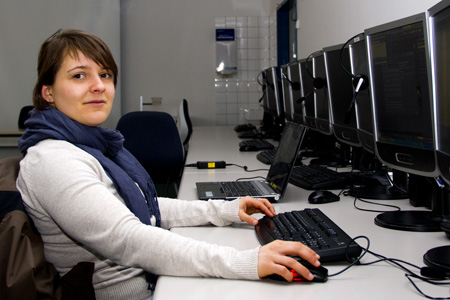 Eine Frau mit blauem Schal, sitzt in einem Computerlabor.