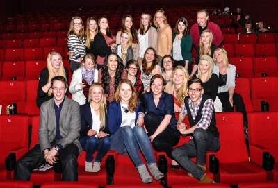 Viele Studentinnen und ein paar Studenten, posieren auf den roten Sesseln des Kinosaals.