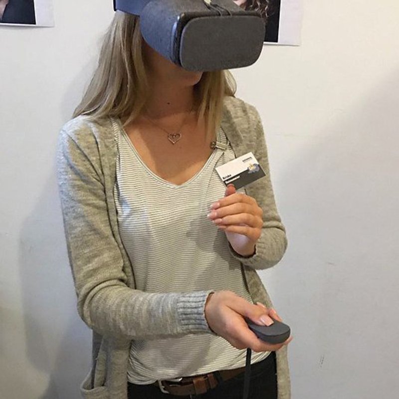 Eine Frau mit VR-Brille und Fernbedienung.