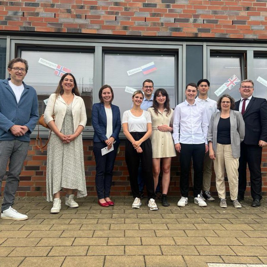 neun Personen posieren für ein Gruppenfoto anlässlich des Besuchs des Attaches der französischen Botschaft Berlin an der FH Kiel vor dem International Office