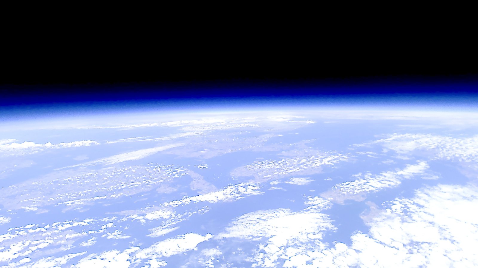 Die Erde abgebildet aus dem Weltall, man sieht leicht bläulich schimmernd die Atmosphäre.
