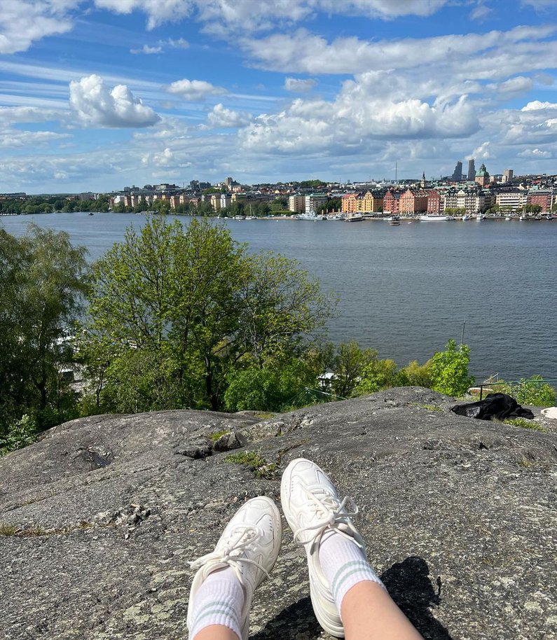 Emelys Füße auf einem Stein am Wasser mit Blick auf die Häuser Stockholms