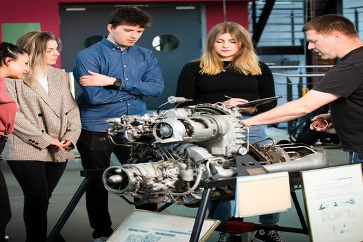 Students and a lecturer looking at an engine