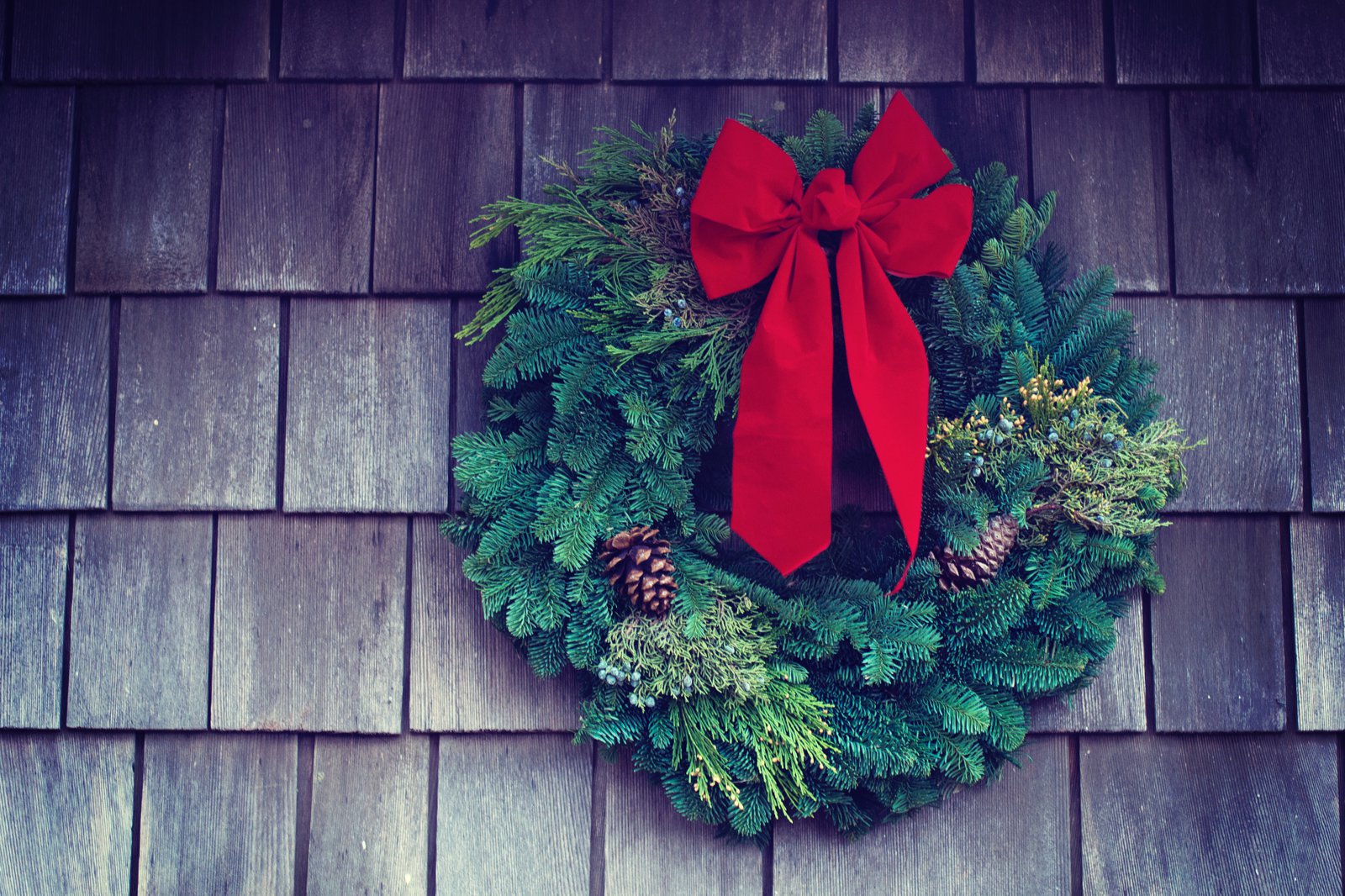 Ein grüner Weihnachtskranz hängt an einer hölzernen Wand.