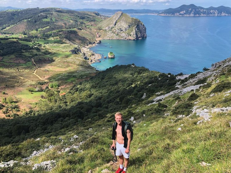Tim beim Wandern oben auf einem Berg mit Blick ins Tal und das Meer