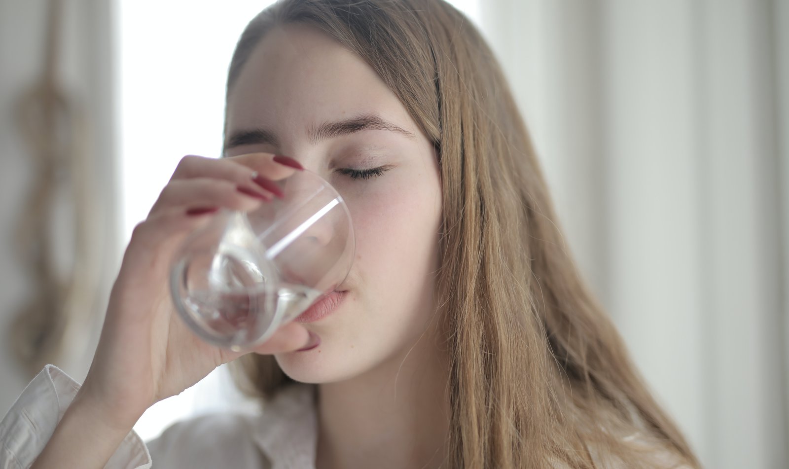 Eine junge Frau trinkt ein Glas Wasser.