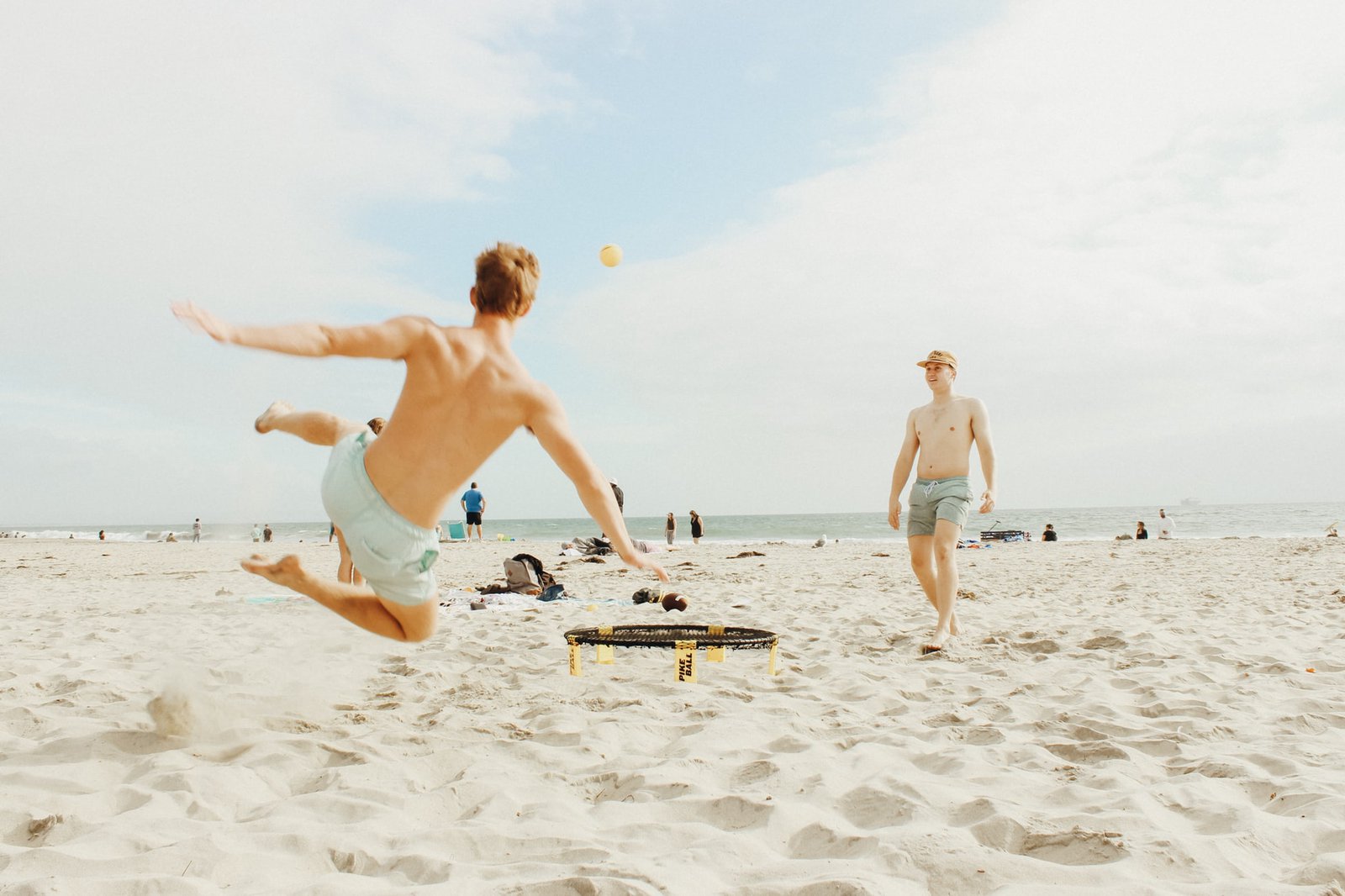 Zwei Männer spielen Ball am Strand.