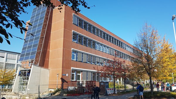 Ein Universitätsgebäude an dem mehrer Solarplatten angebracht sind.