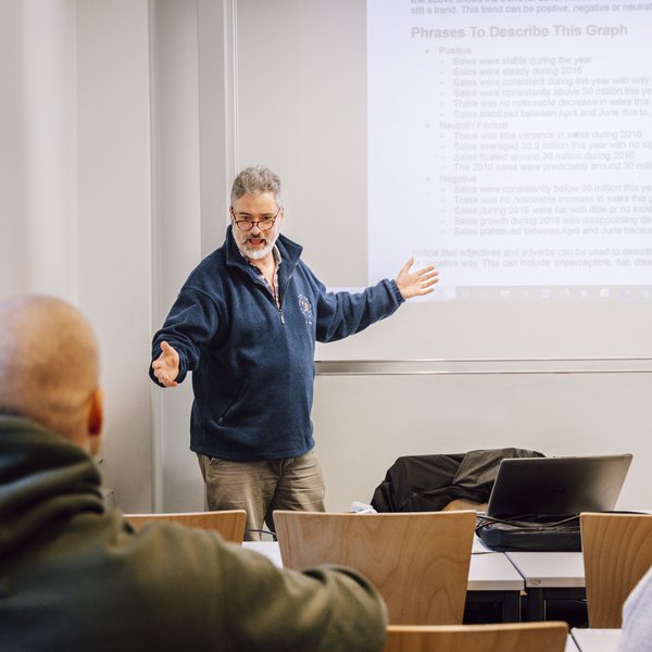 ein Dozent spricht zu zwei Kursteilnehmenden im Seminarraum der FH Kiel 