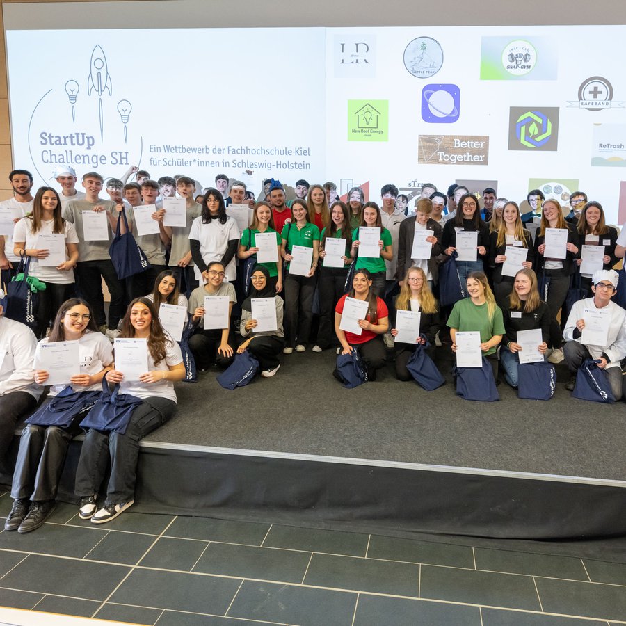 auf der Bühne des Audimax der FH Kiel stehen viele Schülerinnen und Schüler. Sie haben an dem Finale der StartUp Challenge 2023 teilgenommen