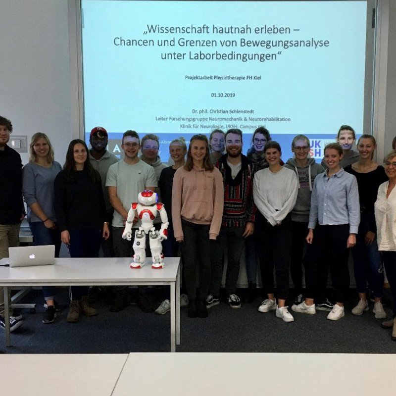 Gruppenbild, vorne ein Tisch mit kleinem Roboter