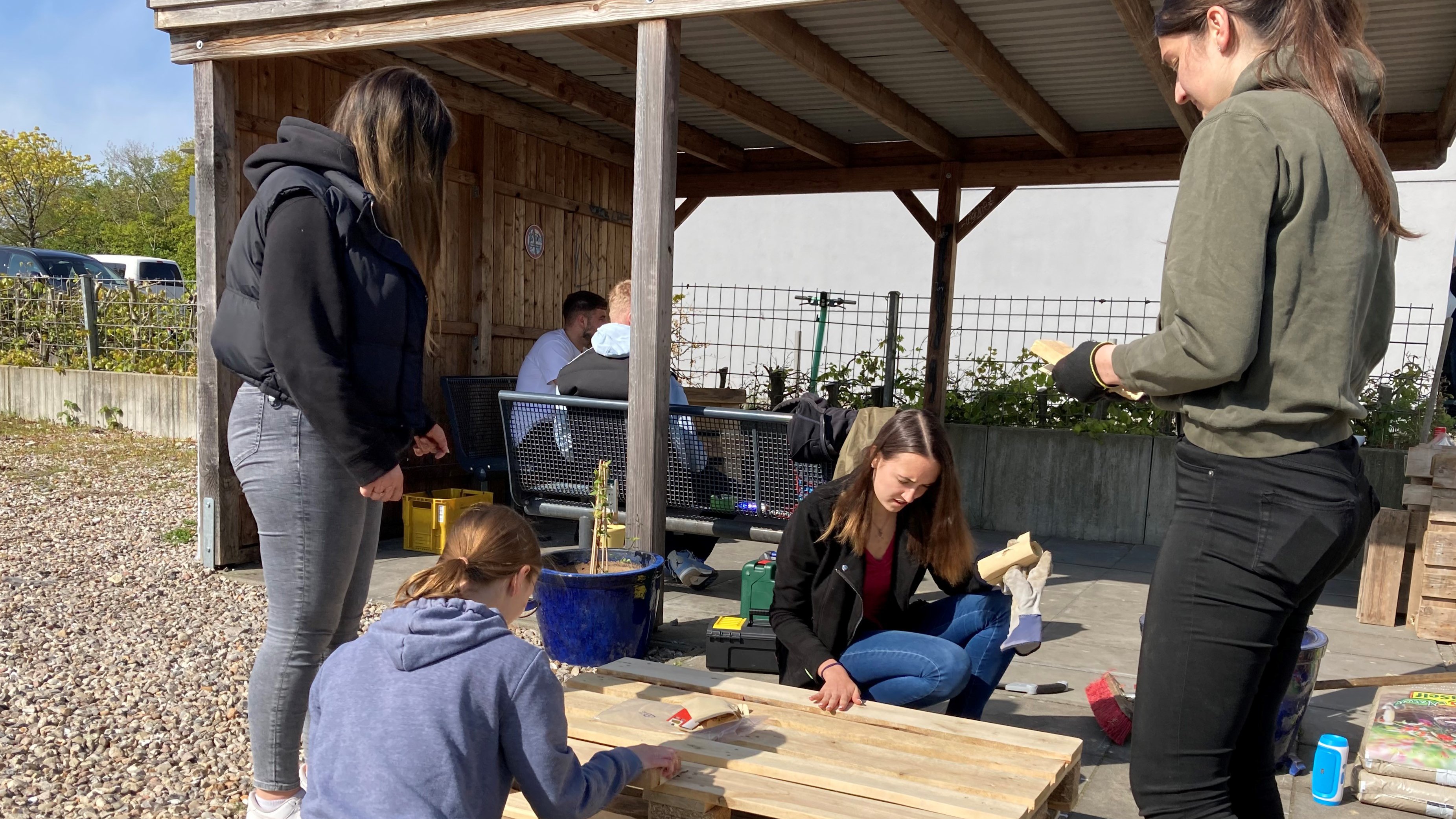 Schüler*innen und Studierende schleifen Europaletten, um daraus Möbel zu bauen