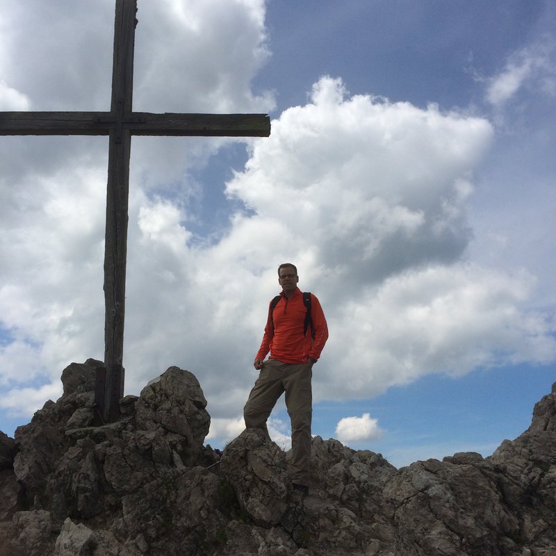 Mann an einem Gipfelkreuz