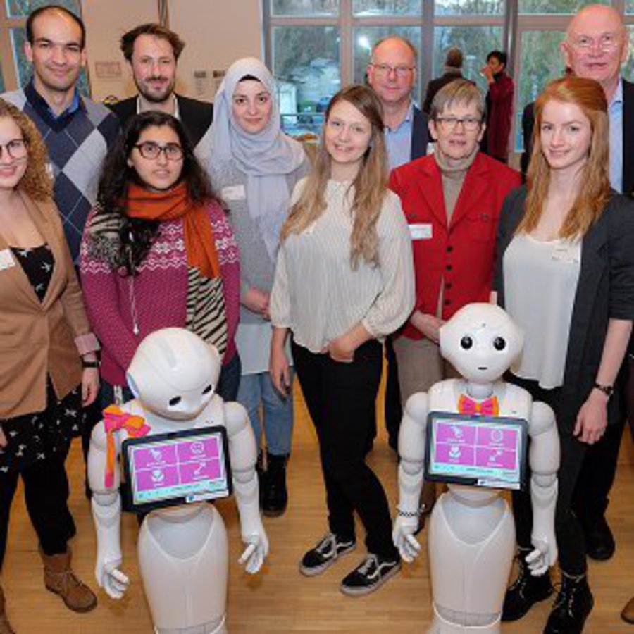 Gruppenbild mit Roboetrn: Forscherinnen und Forscher der FH Kiel und der Uni Siegen mit ihren Pepper-Robotern 