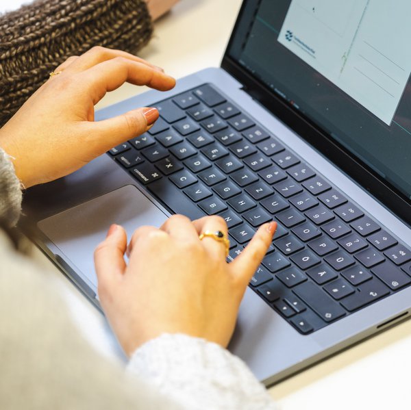 Blick auf Hände einer Studentin, die an ihrem Laptop arbeitet
