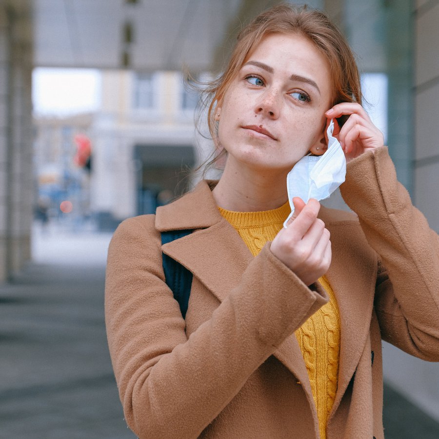 Frau nimmt OP-Maske ab