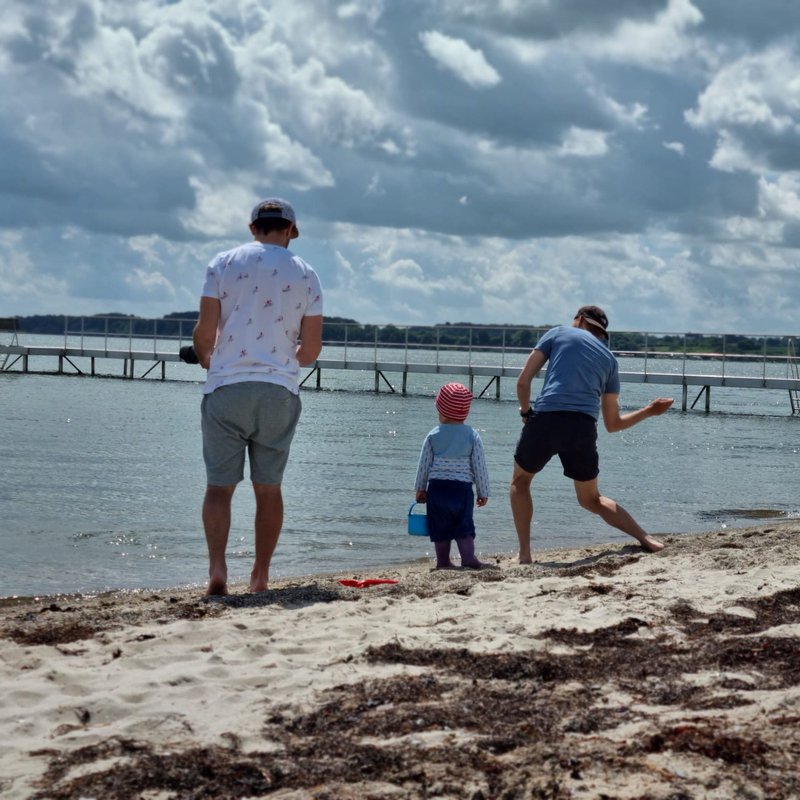 Ein Mann mit zwei Kindern am Strand.