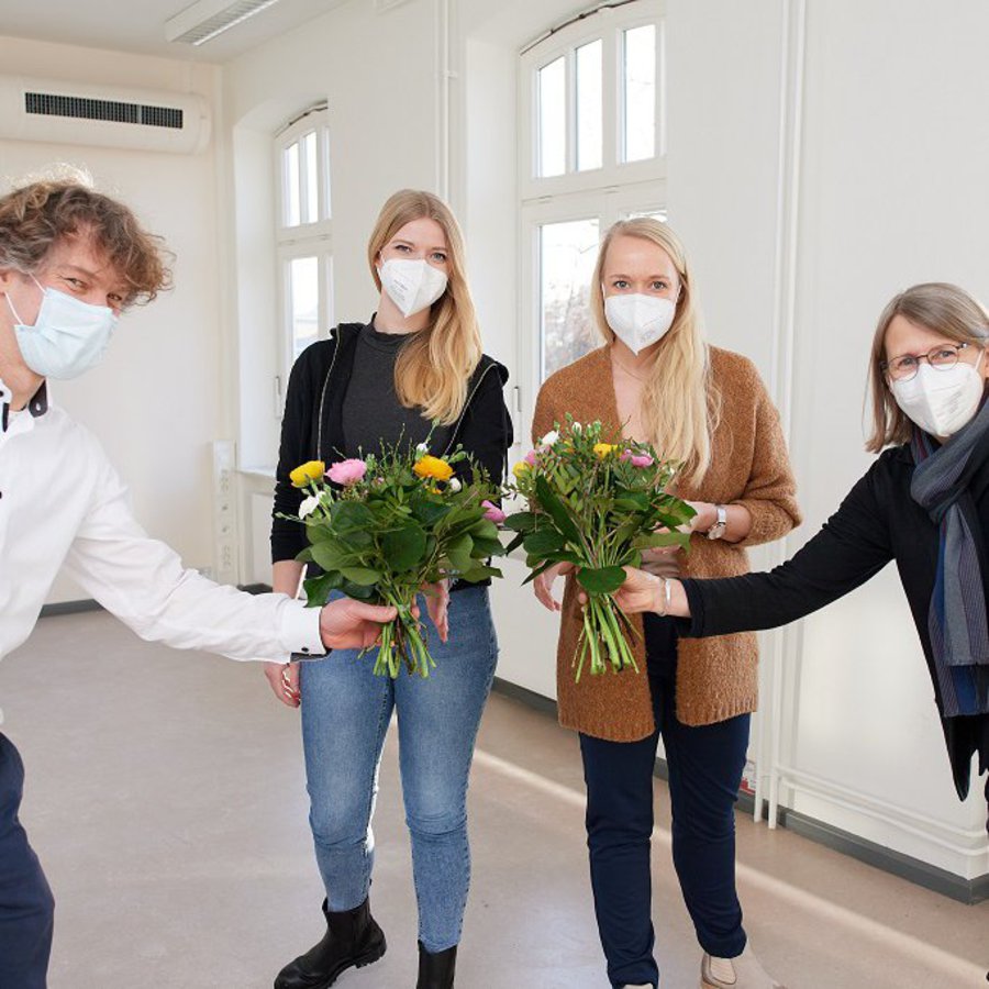 Prof. Woelk und Prof.in Kjär überreichen Rieke Albers und Jennifer Böse Blumen.