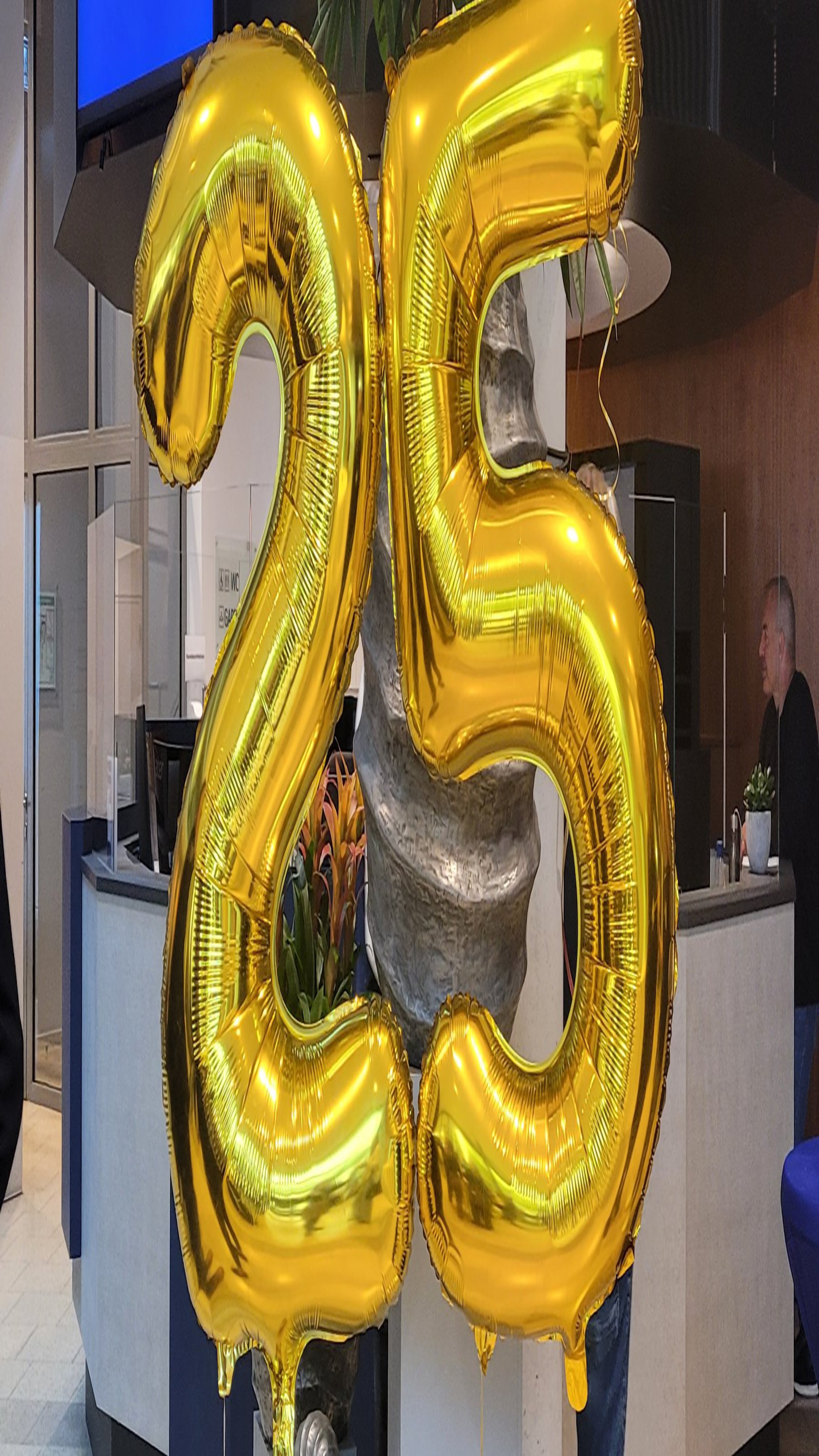 Zwei goldene Luftballons in der Form einer Zwei und einer Fünf. 