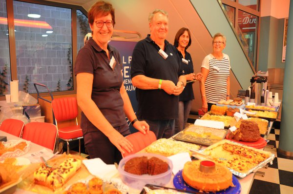 Drei Frauen und ein Mann stehen hinter dem Catering und bieten Speisen an.