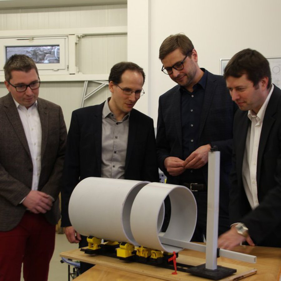 Prof. Christian Keindorf, Stefan Sievers, Eckhard Anders und Prof. Alexander Mattes im Labor mit einem Querschnittsmodell des Turms einer Windkraftanlage