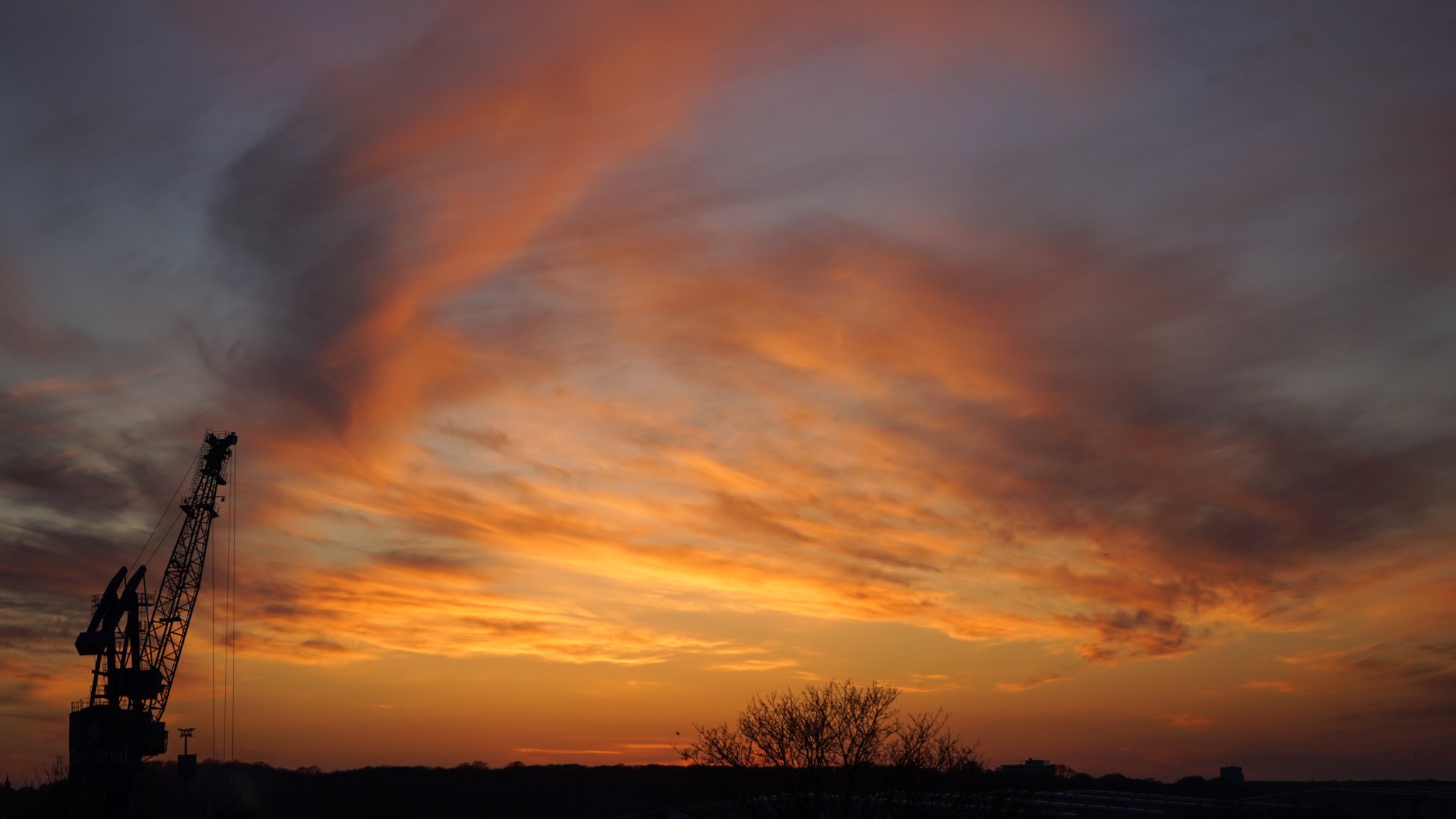 Dramatischer Sonnenuntergang, links im Bild ein Kran