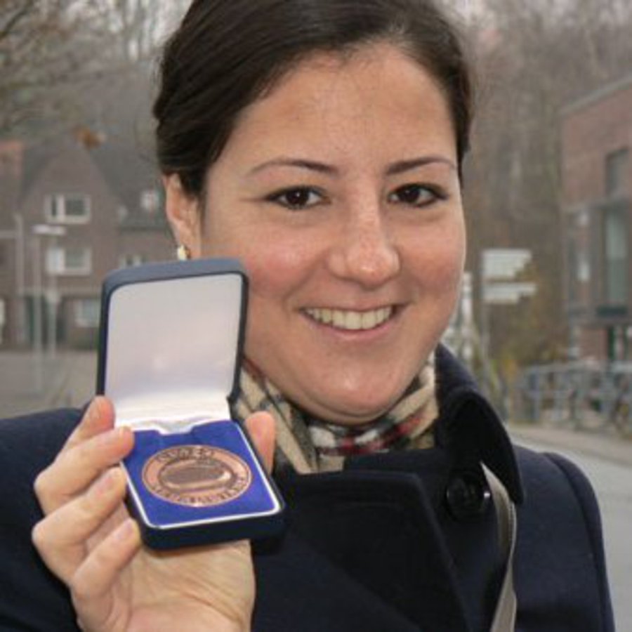 Eine Frau hält stolz ihre Gold-Medaille in die Kamera.