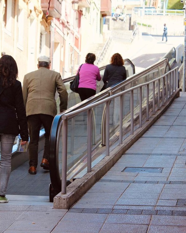 Menschen auf Rolltreppe über steile Straßen