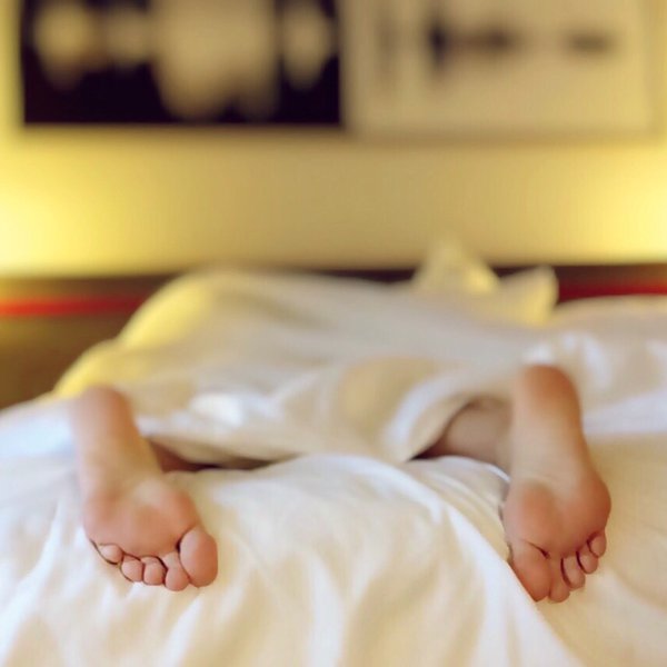 Person im Bett zugedeckt von einer Decke
