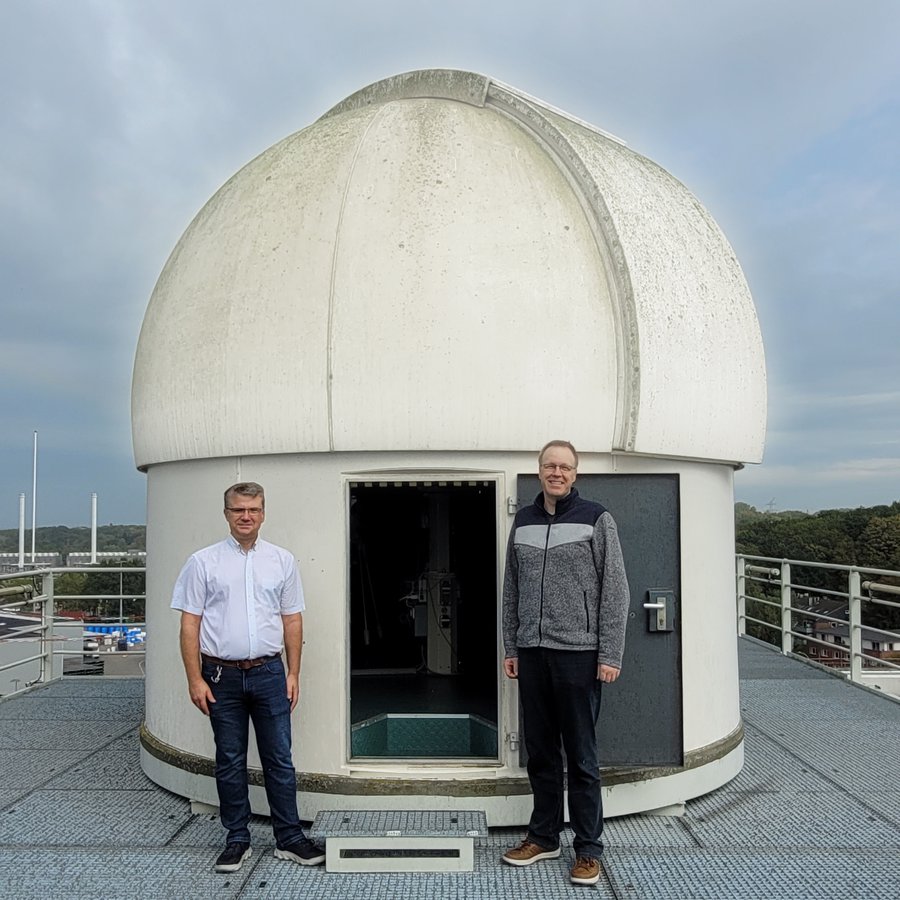 Zwei Männer stehen vor der Kuppel einer Sternwarte
