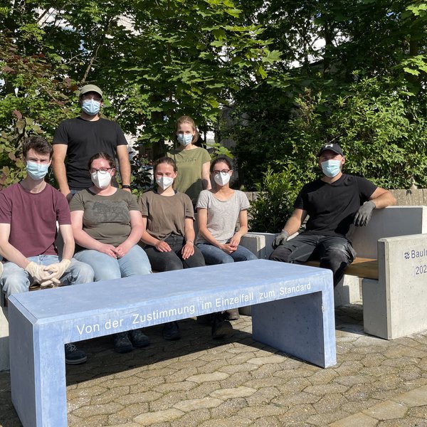 Studierende an der von ihnen gerade aufgebauten Sitzbank aus Beton.