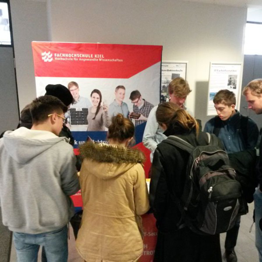 Eine Gruppe Schüler ringt um einen Infostand