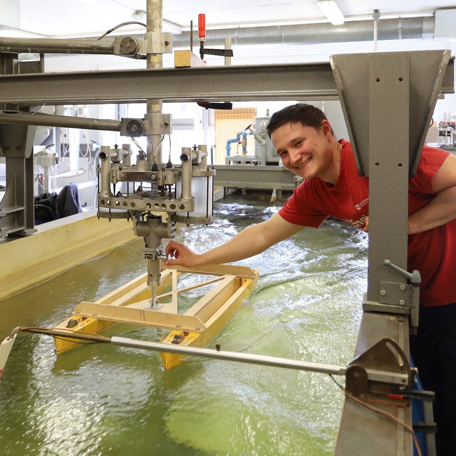 zwei Männer mit Schiffsmodell am Wasserbecken