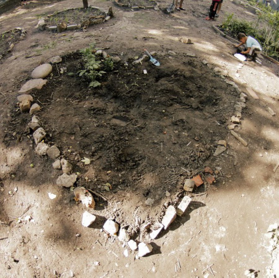 In einem breit angelegten Garten ist ein aus Steinen geformtes Herz zu sehen.