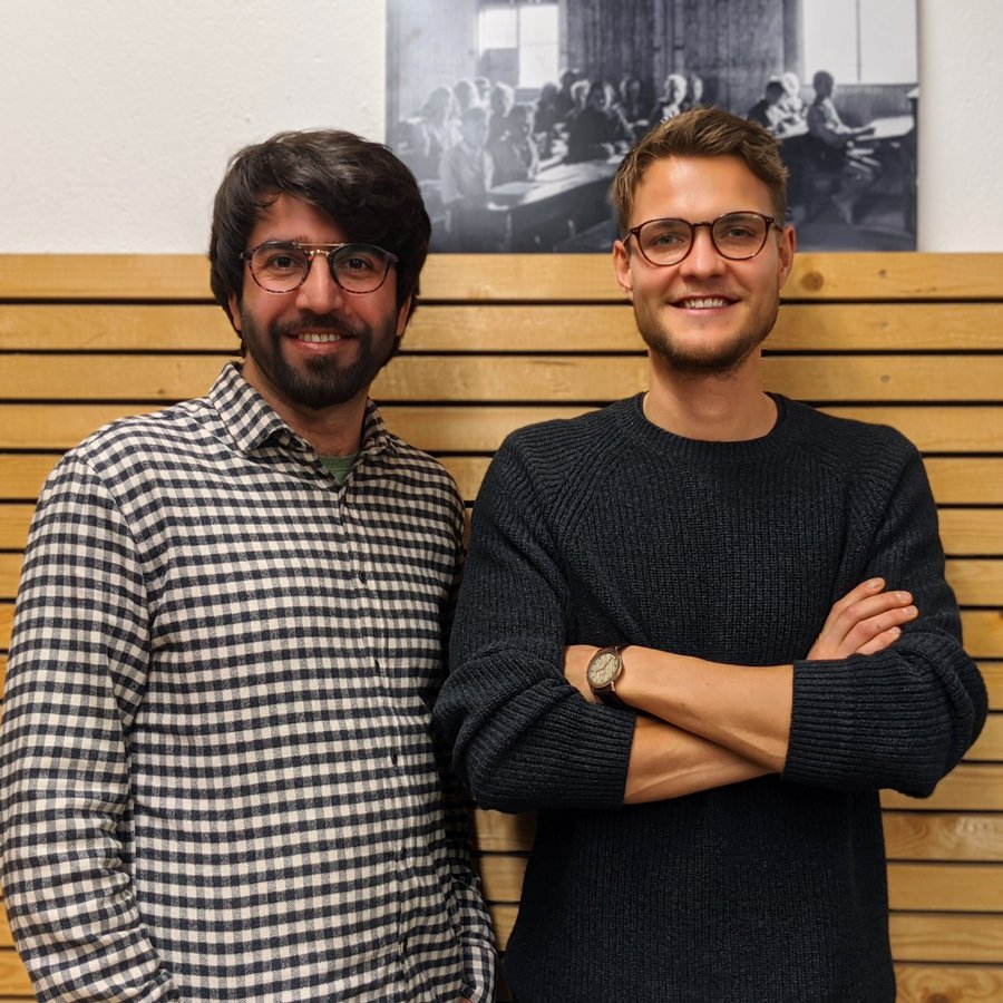 Tayyab Saeed und Jan Peter Prigge stehen vor einer Wand. 