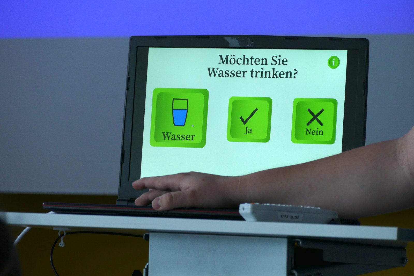 Ein Pult auf dem ein Laptop steht. Der Laptop zeigt eine mögliche Anzeige zur Kommunikation des Service-Roboters.