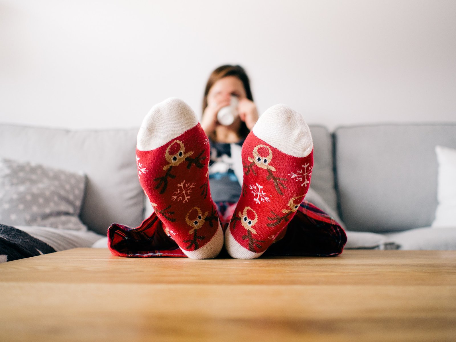 Zwei Füße auf einem Holztische. Die Füße sind mit rot weißen Weihnachtssocken bekleidet.