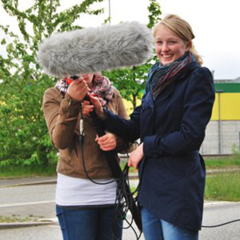 Zwei Frauen halten ein großes Mikrofon, an einer Stange fest.