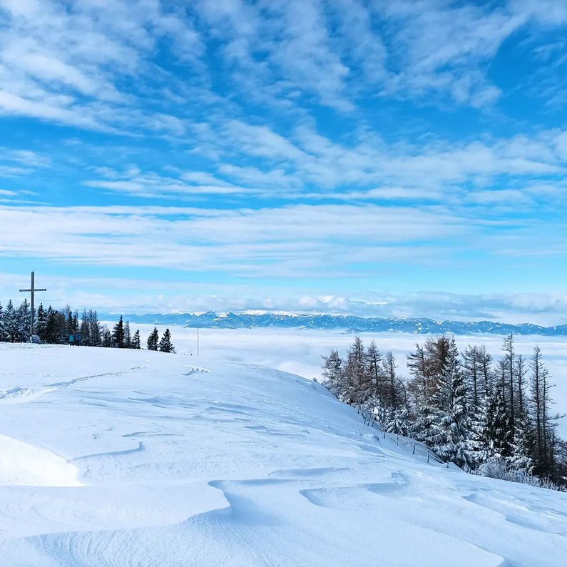 Eine verschneite Szenerie auf Bergen vor strahlend blauem Himmel