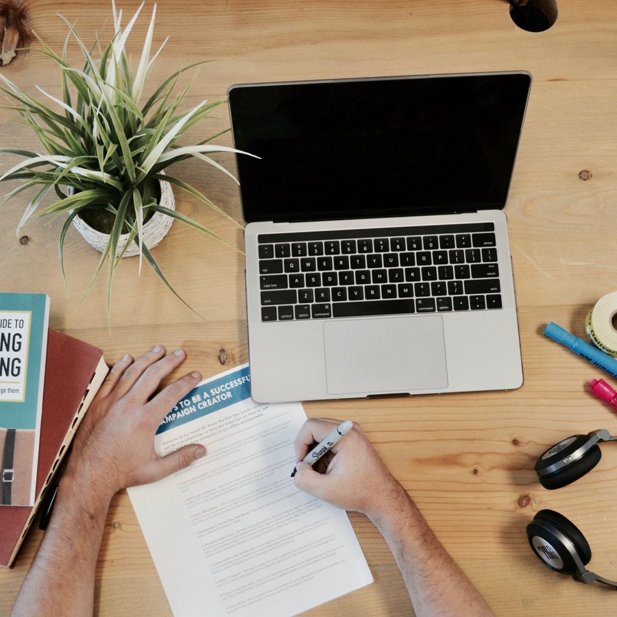 Laptop, Kopfhörer, Notizblock und Bücher