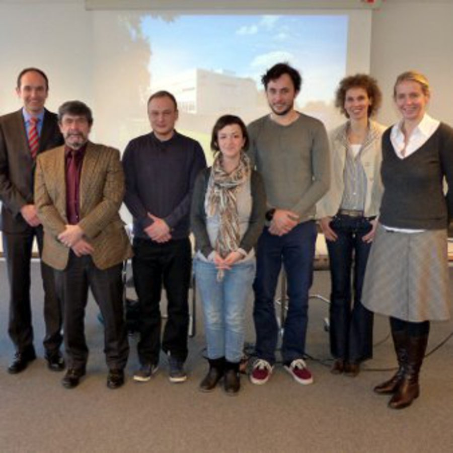 Die Projektgruppe versammelt sich vor der Leinwand, in einem Konferenzraum.