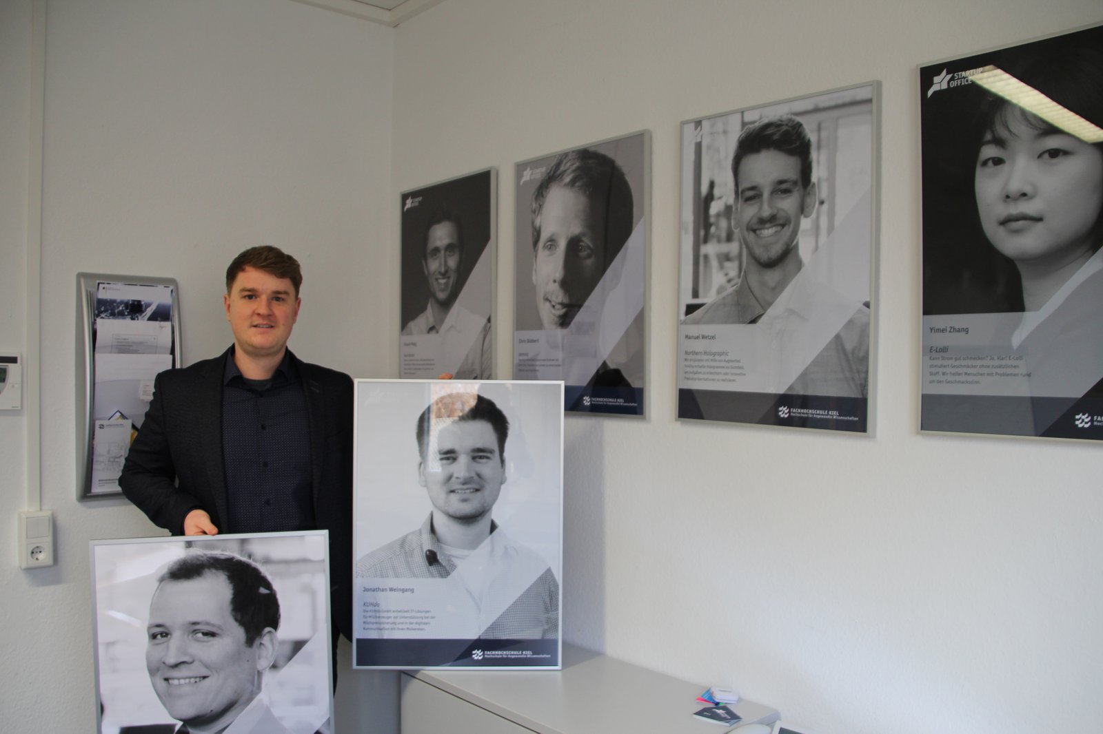 Ein Mann umgeben von Plakat großen Portraits.