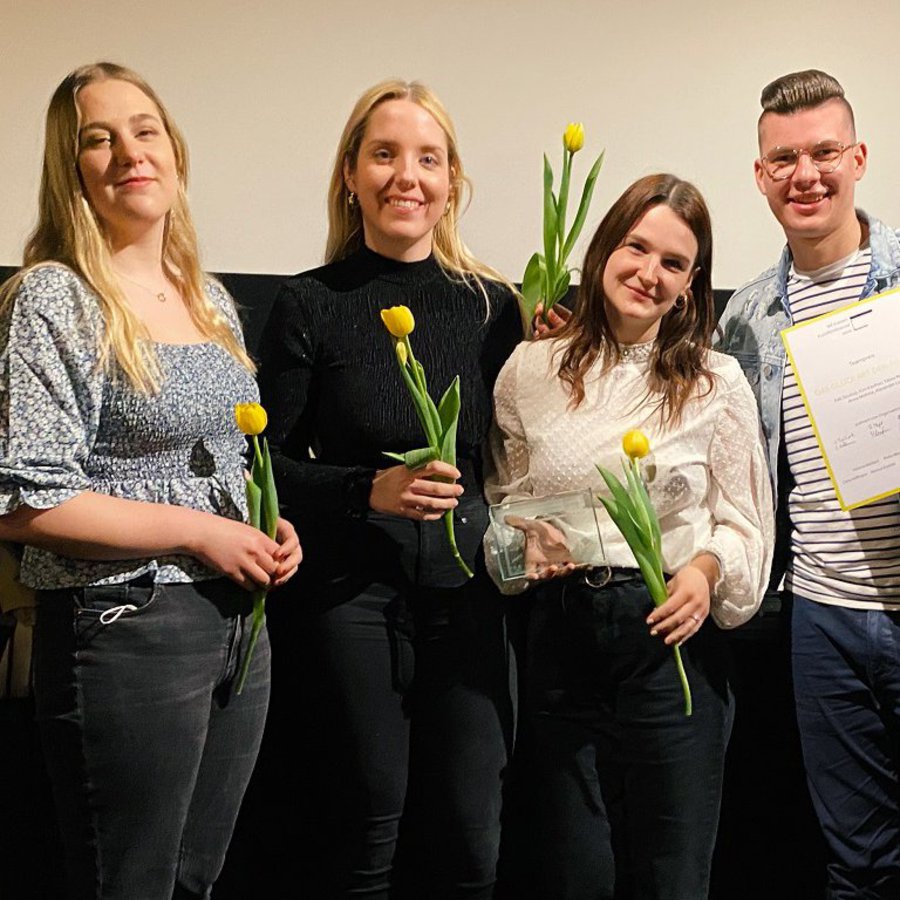 Vier Student*innen stehen nebeneinander mit einer Glastrophäe und Urkunden (v.l.n.r.): Tabea Reinert, Anna Mohme, Kim-Naja Kaufner und Falk Soukup.